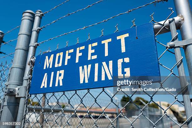 Blue and white stenciled sign for the Moffett Air Wing hanging on a barbed wire fence at Moffett Field, within the secure area of the NASA Ames...