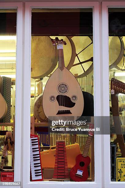 a bouzouki hanging inside of a shop window - musikgeschäft stock-fotos und bilder