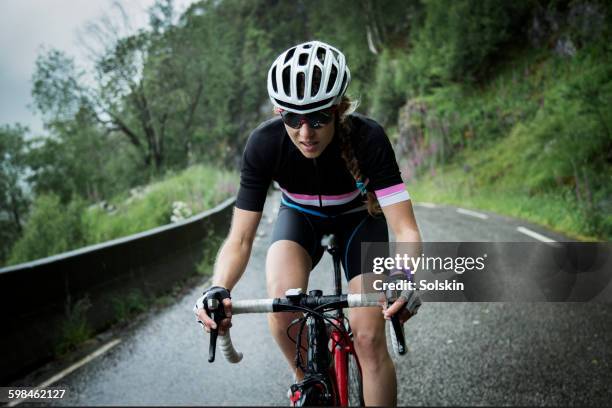 female race cyclist on mountain road - wielrennen stockfoto's en -beelden