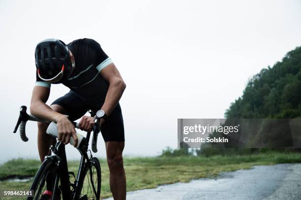 male race cyclist resting by mountain road - exhaustion stock pictures, royalty-free photos & images