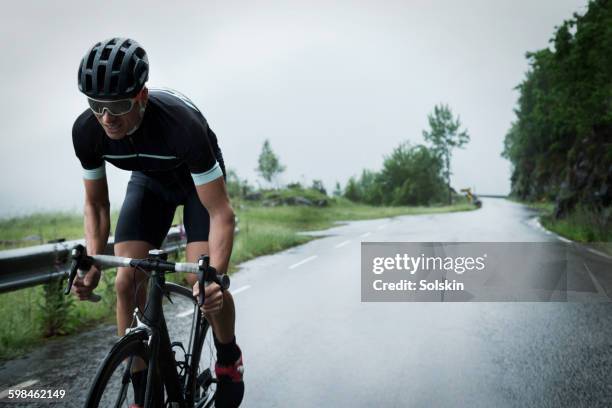 male race cyclist driving up mountain road - ciclista foto e immagini stock