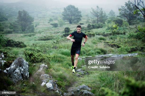 male cross country runner in rocky landscape - cross country running fotografías e imágenes de stock