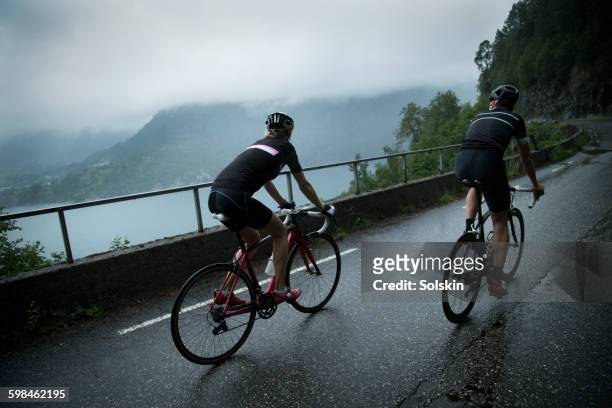 male and female cyclists on mountain road - straßenradsport stock-fotos und bilder
