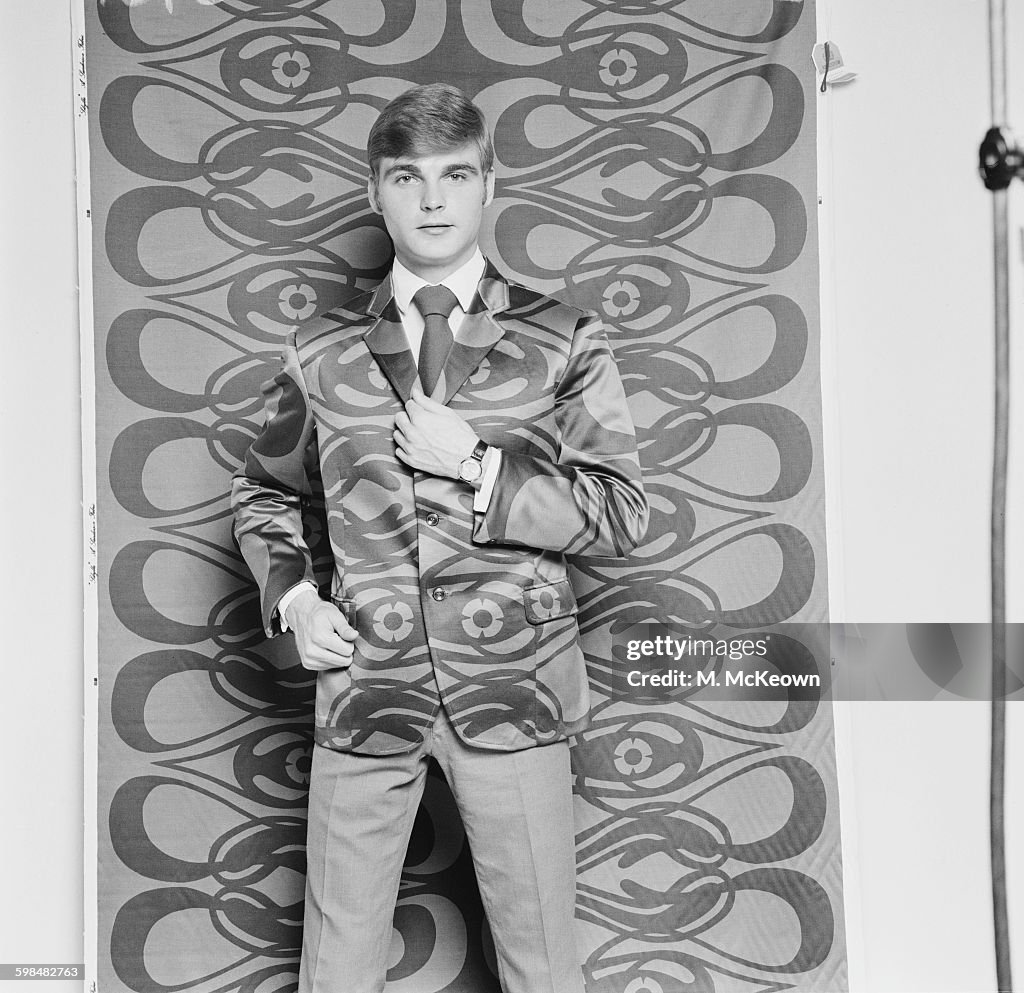 Model Against Patterned Background A male model wearing a patterned jacket by Irvine Sellars, against a ...