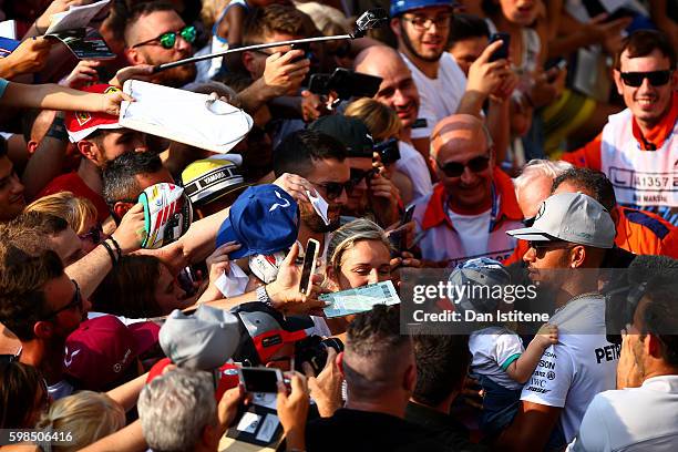Lewis Hamilton of Great Britain and Mercedes GP signs autographs for fans in the Pitlane during previews for the Formula One Grand Prix of Italy at...