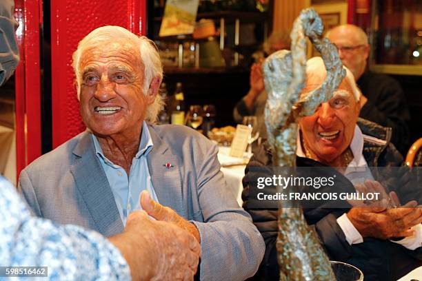 French actor Jean-Paul Belmondo smiles as he shakes hands next to French actor Charles Gerard after being awarded of the "Prix du singe" in reference...