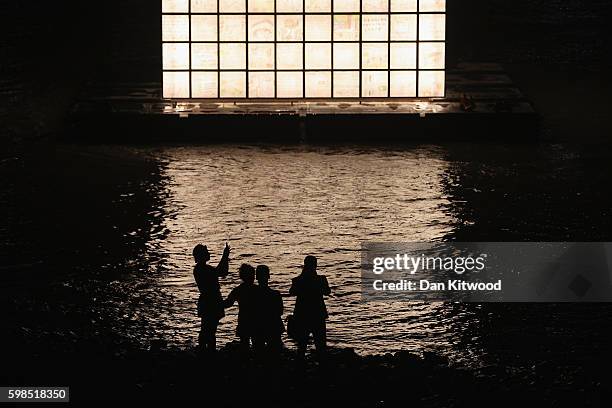 People take photographs of a floating installation in the Thames as installations are lit in front of Tate Modern as part of the 'Fire Garden' event...
