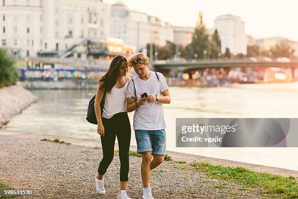 teenage couple mobile gaming outdoors. - boy and girl talking stock pictures, royalty-free photos & images