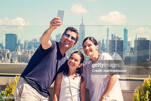 family taking selfie on a rooftop with new-york skyline. - new york vacation rooftop stock pictures, royalty-free photos & images