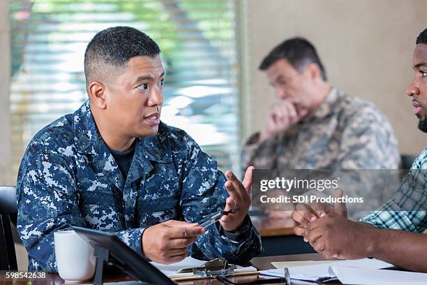 asian soldier explaining duties to man at military recruitment event - recruiter stock pictures, royalty-free photos & images
