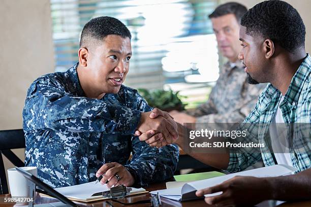 asian soldier meeting with young man at military recruitment event - in dienst gaan stockfoto's en -beelden