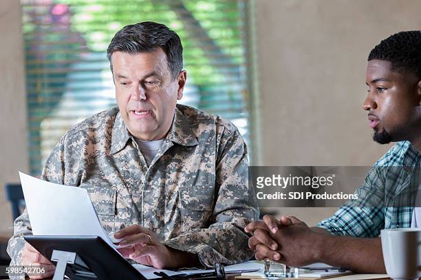 mature military officer meeting with young recruit to discuss enlistment - military recruitment stock pictures, royalty-free photos & images