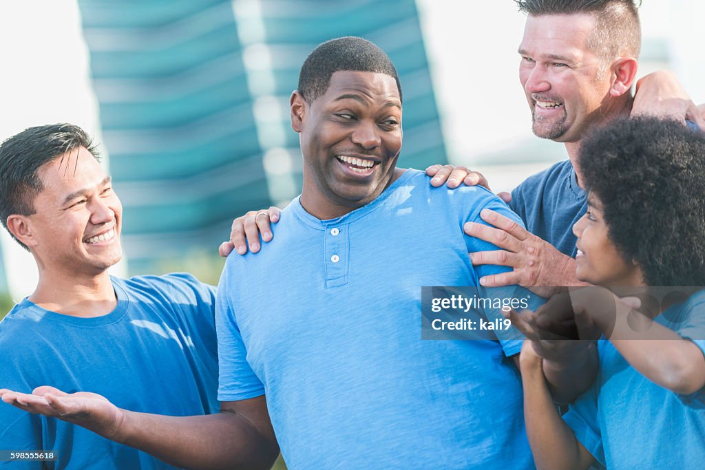 Successful black man getting pat on back from friends