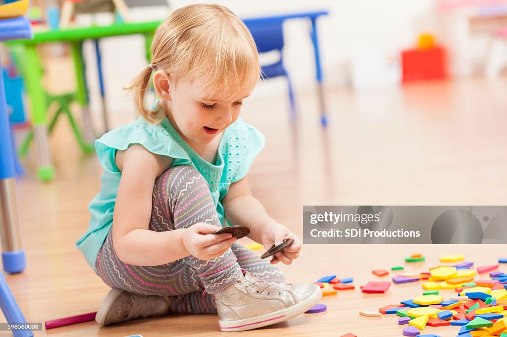 Nettes Kleinkind Mädchen spielen mit Spielzeug auf Kita-Boden