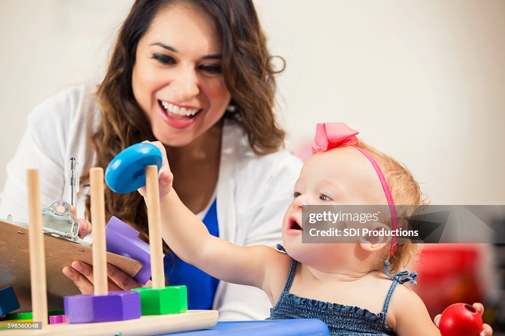 Pretty Hispanic teacher works with cute little preschooler