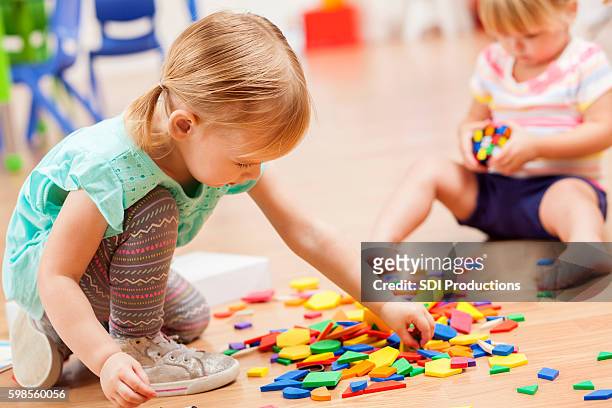 ragazze più piccoli che giocano con pezzi di puzzle in un'aula prescolare - 2 3 anni foto e immagini stock