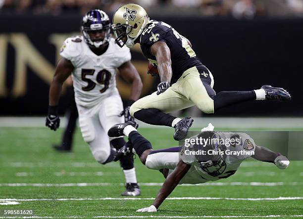 Marcus Murphy of the New Orleans Saints jumps over Tavon Young of the Baltimore Ravens at the Mercedes-Benz Superdome on September 1, 2016 in New...