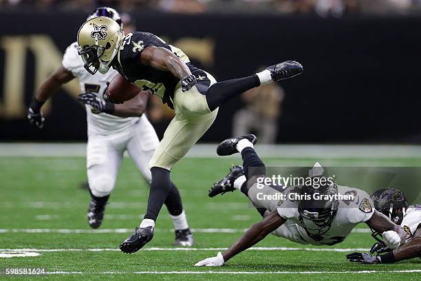 Marcus Murphy of the New Orleans Saints jumps over Tavon Young of the Baltimore Ravens at the Mercedes-Benz Superdome on September 1, 2016 in New...