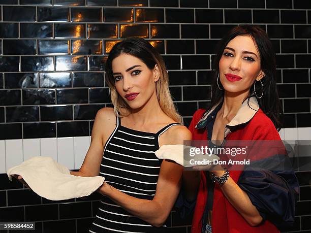 Jess Origliasso and Lisa Origliasso from The Veronicas pose with pizza dough they had been kneading during the launch of Fratelli Famous at Westfield...