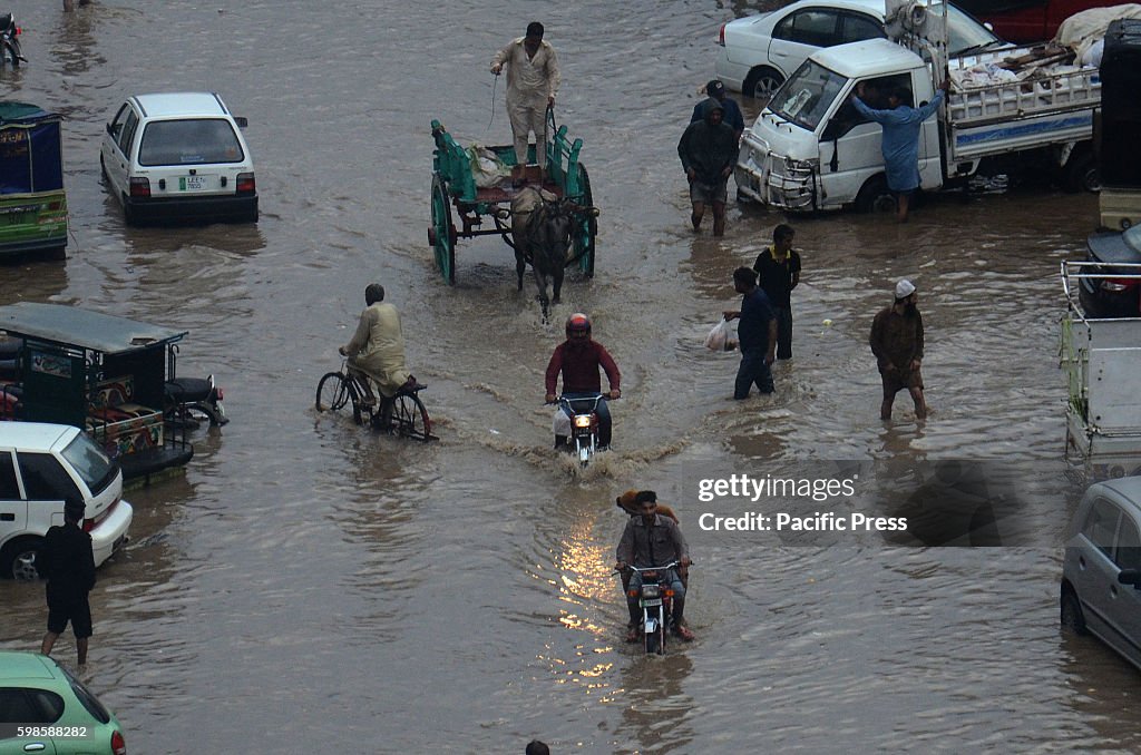 Pakistani people wade through floodwaters during heavy...