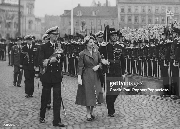 Queen Elizabeth II inspects a company of the King's Guard with King Haakon VII of Norway and Captain Skutle, with the Duke of Edinburgh following...