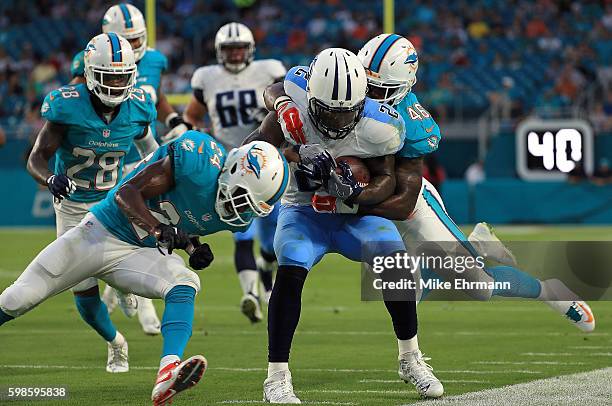 Derrick Henry of the Tennessee Titans is forced out of bounds by Neville Hewitt of the Miami Dolphins during a preseason game at Hard Rock Stadium on...