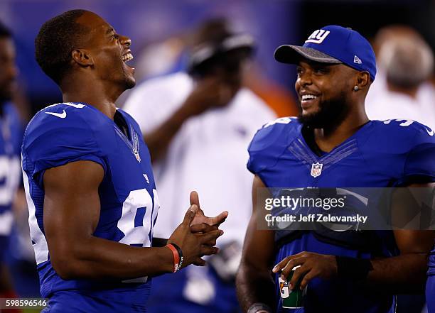 Victor Cruz and Shane Vereen of the New York Giants stand on the sidelines against the New England Patriots during their preseason game at MetLife...