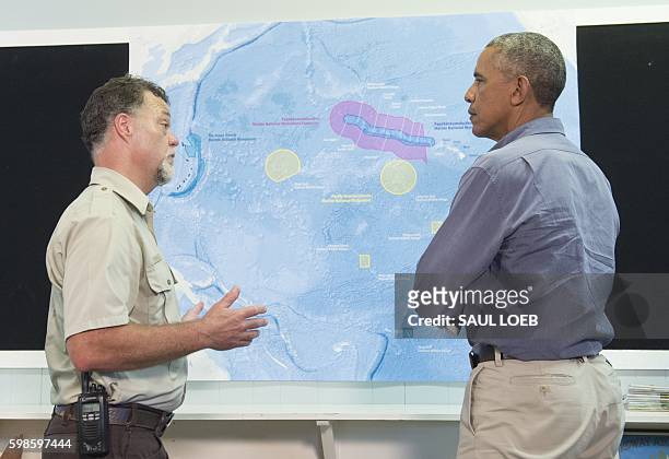 President Barack Obama, alongside refuge manager Bob Peyton, looks at a map of Midway Atoll in the Papahanaumokuakea Marine National Monument in the...