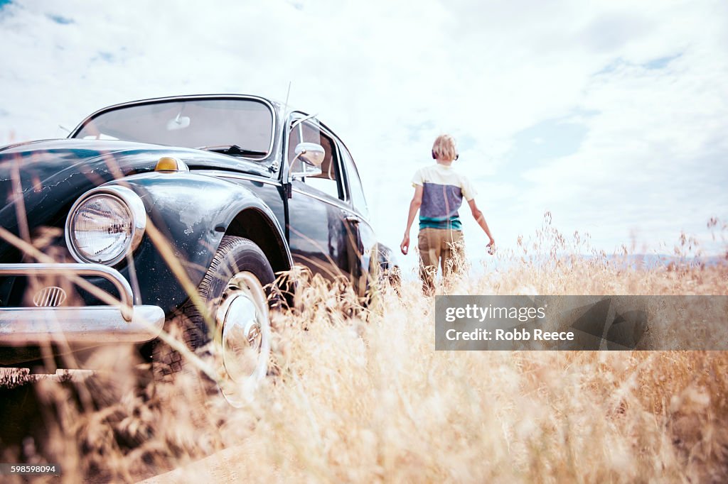 A young, happy boy walking near a 1967 vintage Volkswagen Bug