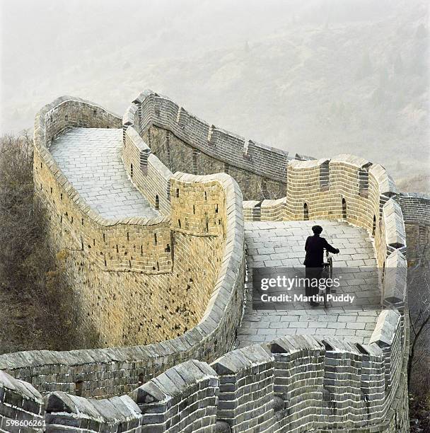 elderly man pushing bicycle along great wall - ユネスコ世界遺産 ストックフォトと画像