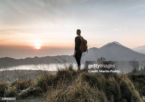 woman standing on mount batur at sunrise - woman rear view stock pictures, royalty-free photos & images