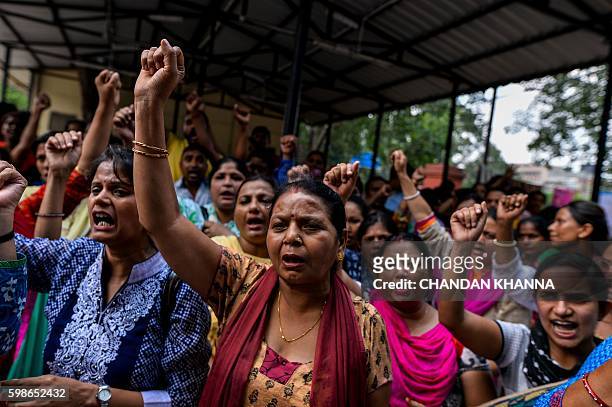 Nurses of Indian government hospital raise hands as they shout slogans during a protest in New Delhi on September 2 during an all India strike staged...