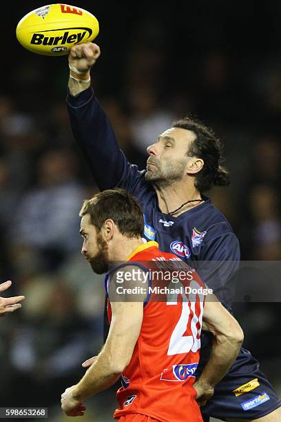 Ang Christou of Victoria punches the ball away from Jason Akermanis of the All Stars during the EJ Whitten Legends match at Etihad Stadium on...