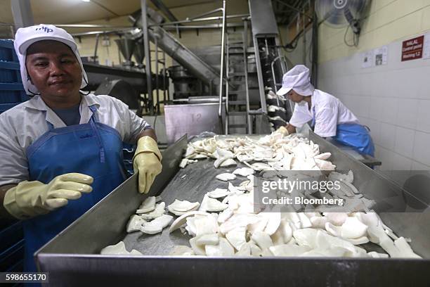 Employees prepare to place chunks of coconut into a grinder at a coconut grinding station of a Merit Food Products Co. Coconut milk factory in...