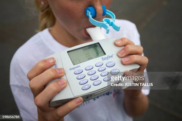 Girl blows into a spirometer during a photocall to promote clean air in central London on September 2, 2016. A Spirometer device measures the volume...