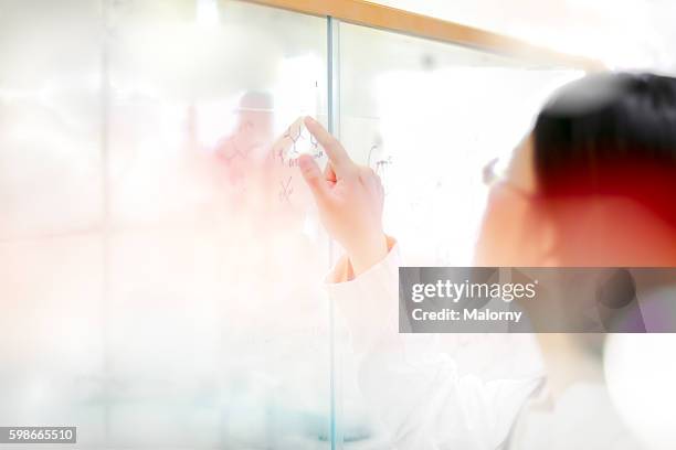 female doctor, pharmaceutical chemist or engineer with white protective workwear working in a modern, bright laboratory. - lab science moderne stockfoto's en -beelden