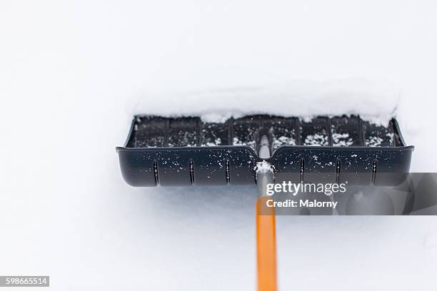 snow shovel in snow, during snowfall. shoveling the snow - winter snow shovel stock pictures, royalty-free photos & images