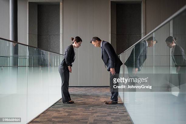 two japanese business people bowing towards each other - david cameron greets the prime minister of japan stockfoto's en -beelden