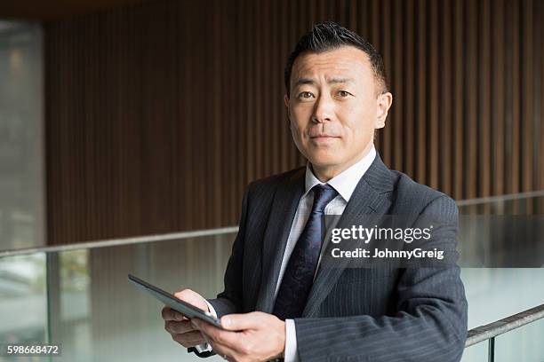 porträt eines reifen japanischen geschäftsmannes mit tablet - japaner stock-fotos und bilder