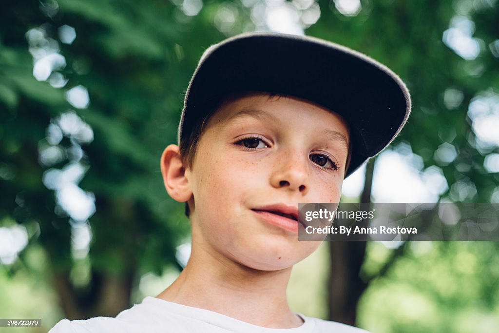 Cute preteen boy in baseball cap looking at camera