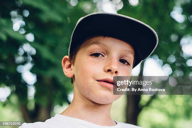 cute preteen boy in baseball cap looking at camera - boy children smirking stock pictures, royalty-free photos & images