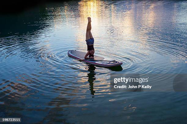 women practicing yoga on a paddleboard - yoga headstand stock pictures, royalty-free photos & images