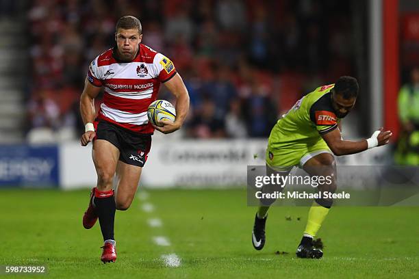 Henry Purdy of Gloucester races away from Telusa Veainu of Leicester on his way to scoring a try during the Aviva Premiership match between...