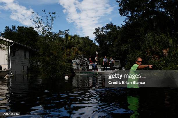 Resident points back to his home as he speaks with law enforcement officers using an airboat to survey damage around homes from high winds and storm...