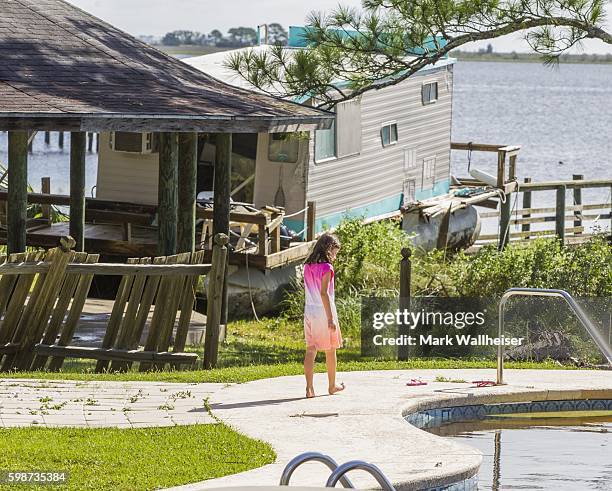 Maddie Mitchell, 8 years old, walks around her grandfather's pool as a houseboat sits on top of a dock carried there by the storm surge from...