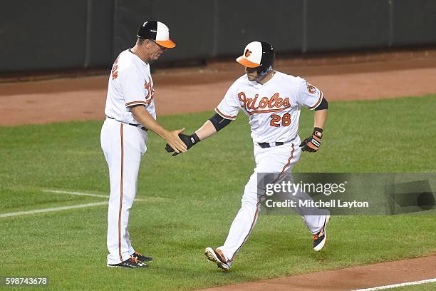 Steve Pearce of the Baltimore Orioles celebrates a home run with third base coach Bobby Dickerson a baseball game against the Toronto Blue Jays at...