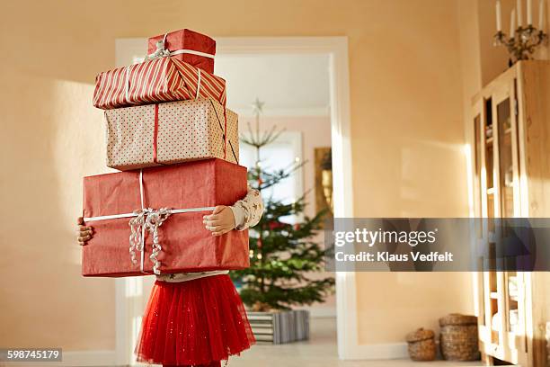 girl holding tall stack of christmas presents - kerstkado stockfoto's en -beelden