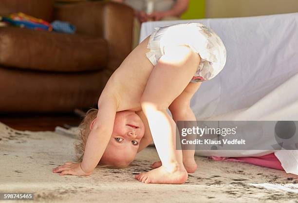 cute toddler standing on head and smiling - luier stockfoto's en -beelden