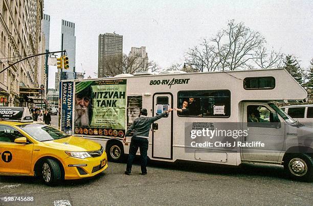 Jewish man high fives Jewish children in a motor home labelled as a "Mitzvah Tank" during a parade of similar vehicles down 5th Avenue in Manhattan,...