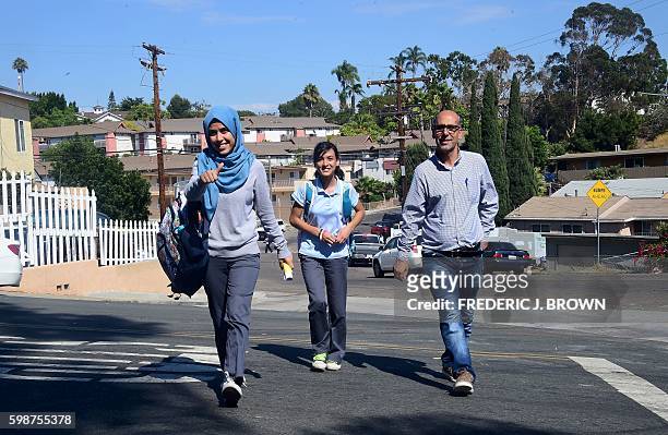 Syrian refugee Ammar Kawkab crosses the street with his daughters Noor and Aya as they make their way home from school in San Diego on August 31,...